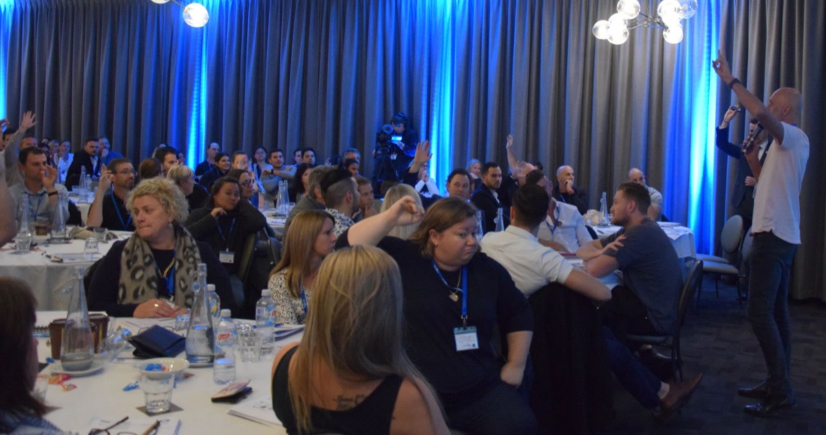 Attendees with hands raised at a Remarkable Practice event